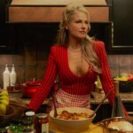 Angela Norris (Ali Larter) in a red striped dress preparing dinner in her kitchen, showcasing her bold, glamorous personality in Landman.