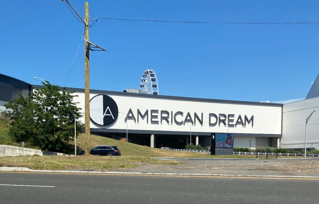 Exterior of American Dream mall with Ferris wheel in background, representing consumerism and industrial ambition explored in Landman series.