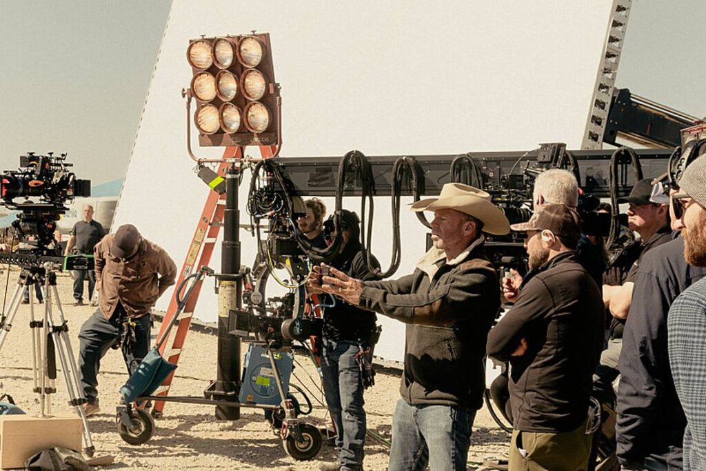 Landman Season 2 production team filming on outdoor location in Texas with director, lighting crew, and multiple camera operators on site.