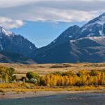 Majestic Montana mountains with golden autumn trees, representing the iconic natural backdrop of Yellowstone and its sprawling land battles.